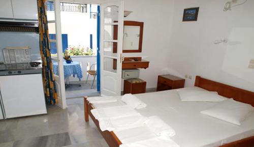 a room with a bed and a kitchen with a table at Studios Rea Sun in Naxos Chora