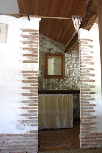 a room with a stone wall and a mirror at Maison Basta in Orthevielle