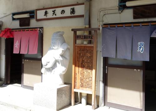 a statue in front of a building with a sign at Izu no Ie UNO in Ito