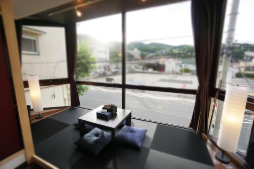 a room with a large window with a table and pillows at Izu no Ie UNO in Ito