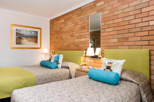 a hotel room with two beds and a brick wall at Ningana Motel in Mudgee