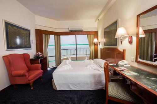 a hotel room with a bed and a desk and a chair at Rainbow Paradise Beach Resort in George Town