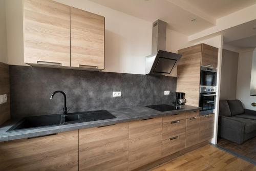 - une cuisine avec des placards en bois, un évier et un canapé dans l'établissement Les Gites Historiques, à Mirecourt