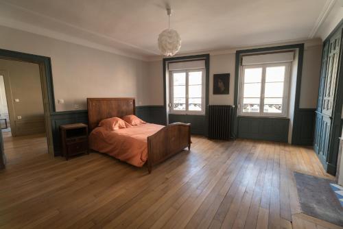 a bedroom with a bed and wooden floors and windows at Les Gites Historiques in Mirecourt