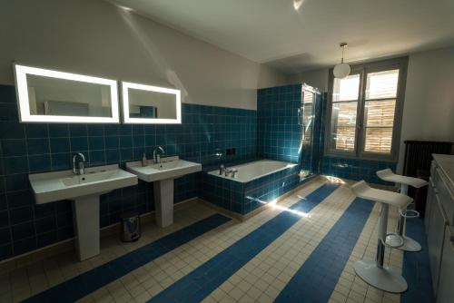 a blue tiled bathroom with two sinks and a tub at Les Gites Historiques in Mirecourt