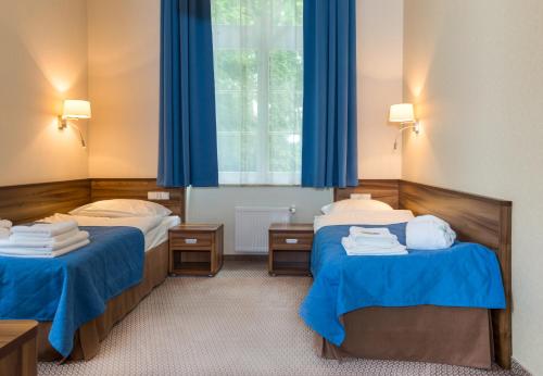 two beds in a room with blue curtains at Edward in Jelenia Góra