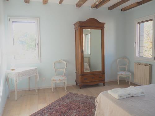 a bedroom with a dresser and two chairs and a mirror at Casa Mongolfiere Venezia in Venice