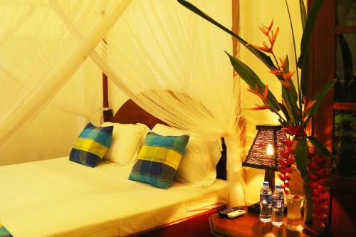 a bedroom with a canopy bed with pillows and a lamp at Villa Bird Gate in Galle