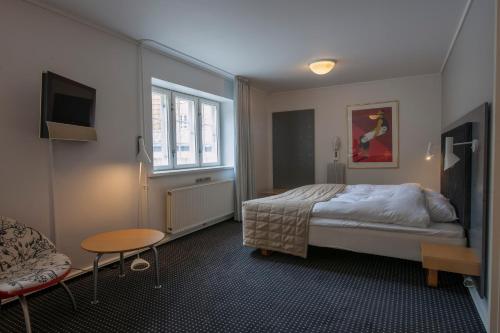 a bedroom with a bed and a table and a couch at Hotel Koldingfjord in Kolding