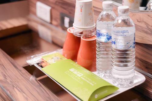 a tray with bottles of water and a book on a table at Guest Motel- Zhongli Branch in Pingzhen