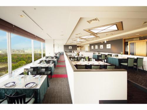 a dining room with tables and chairs and windows at KKR Hotel Osaka in Osaka