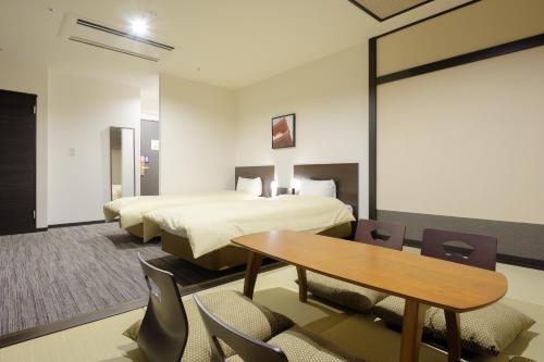The Premium Hotel In Rinku في إيزوميسانو: غرفة فندقية بسريرين وطاولة وكراسي