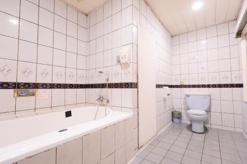 a white bathroom with a tub and a toilet at Guest Motel- Zhongli Branch in Pingzhen