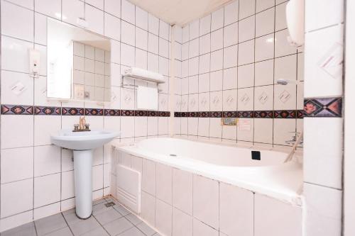 a white bathroom with a tub and a sink at Guest Motel- Zhongli Branch in Pingzhen