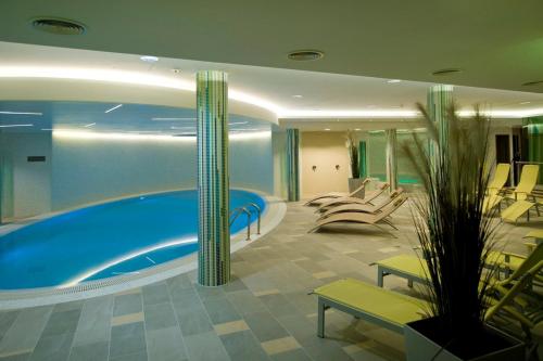 a large swimming pool in a hotel room with chairs at Jankovich Hotel in Rácalmás