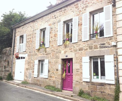 un bâtiment en briques avec une porte et des fenêtres roses dans l'établissement Chez Catie, à Quintin