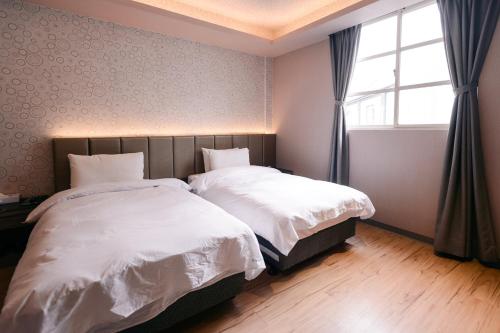 a bedroom with two beds and a window at Guest Motel- Zhongli Branch in Pingzhen