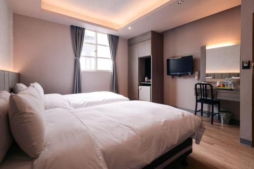 a bedroom with a large white bed and a desk at Guest Motel- Zhongli Branch in Pingzhen