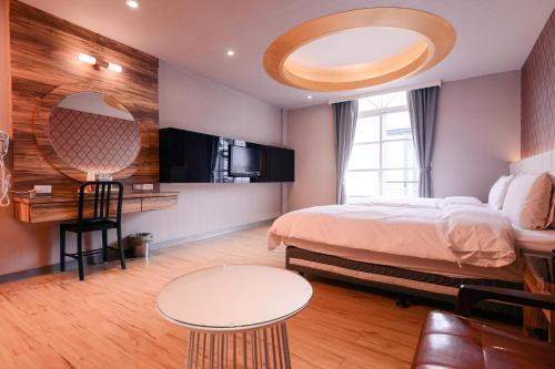 a bedroom with a bed and a table and a mirror at Guest Motel- Zhongli Branch in Pingzhen