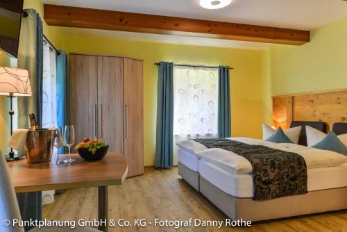 ein Schlafzimmer mit einem großen Bett und einem Holztisch in der Unterkunft Hotel Oberwirt in Obing