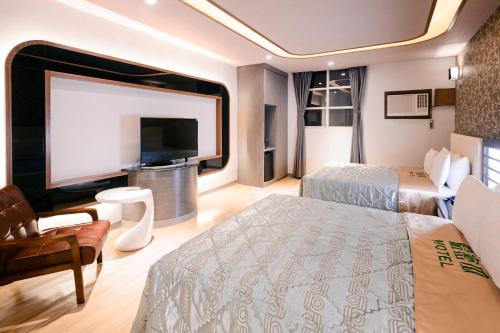 a hotel room with two beds and a flat screen tv at Guest Motel- Zhongli Branch in Pingzhen