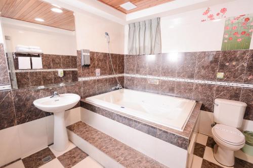 a bathroom with a tub and a toilet and a sink at Guest Motel- Zhongli Branch in Pingzhen