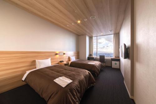 a hotel room with two beds and a window at Izumisano Center Hotel Kansai International Airport in Izumi-Sano