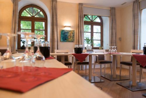 a dining room with tables and chairs and windows at Hotel Angerbräu in Murnau am Staffelsee