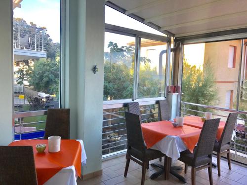 een eetkamer met een rode tafel en stoelen op een balkon bij Hotel Aurora in San Vincenzo