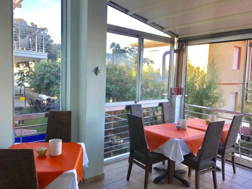 comedor con mesa roja y sillas en el balcón en Hotel Aurora, en San Vincenzo