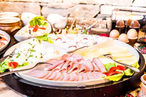 a plate of food with meat and vegetables on a table at Villa Magnat SPA, JACUZZI, SAUNA, TĘŻNIA SOLANKOWA in Białka Tatrzanska