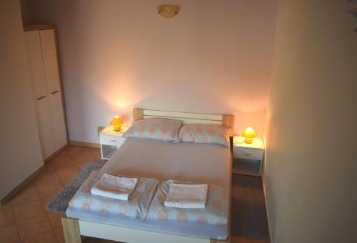 um pequeno quarto com uma cama com duas mesas de cabeceira em Apartment Bini em Molunat