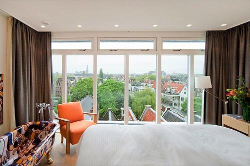 a bedroom with a bed and a large window at The Bank Hotel in Amsterdam