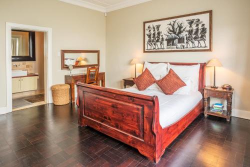a bedroom with a large wooden bed with pillows at Antrim Luxury Villa in Cape Town