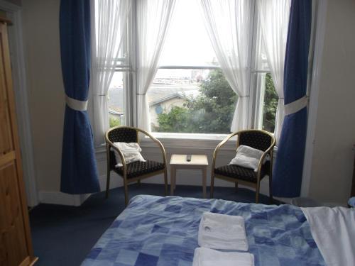 een slaapkamer met een bed en 2 stoelen en een raam bij beaufort guesthouse in Weymouth
