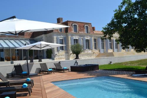 une piscine avec chaises et parasols à côté d'un bâtiment dans l'établissement Chateau Prieure Marquet, à Saint-Martin-du-Bois