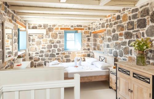 a bathroom with two beds and a stone wall at Pserimos Villas in Psérimos
