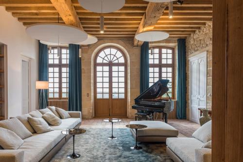 a living room with a couch and a piano at Chateau Prieure Marquet in Saint-Martin-du-Bois