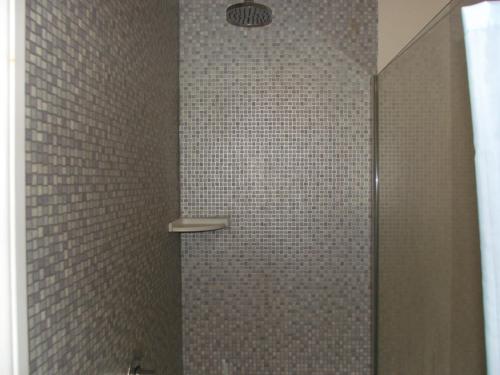 een badkamer met een douche en een betegelde muur bij beaufort guesthouse in Weymouth