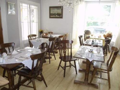 a dining room with tables and chairs with white tablecloths at beaufort guesthouse in Weymouth