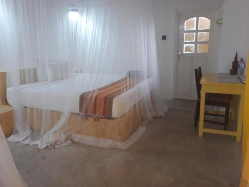 a bedroom with a bed with white curtains and a desk at Randoni Villa in Raddoluwa