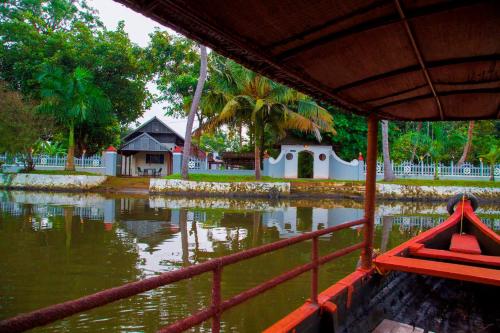 a boat in a body of water with a house at Kurialacherry House Alleppey in Ambalapulai