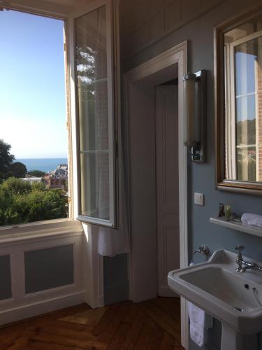 une salle de bain avec un lavabo et une fenêtre dans l'établissement Castel De La Terrasse, à Étretat