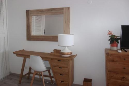 een bureau met een lamp en een spiegel aan de muur bij Colibri des îles in Le Gosier