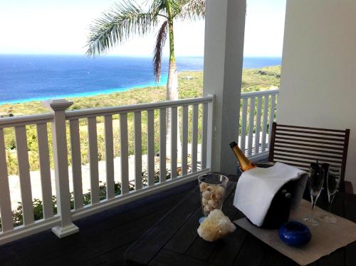 a table on a balcony with a view of the beach at Great View Villa Galant Curaçao in Willibrordus