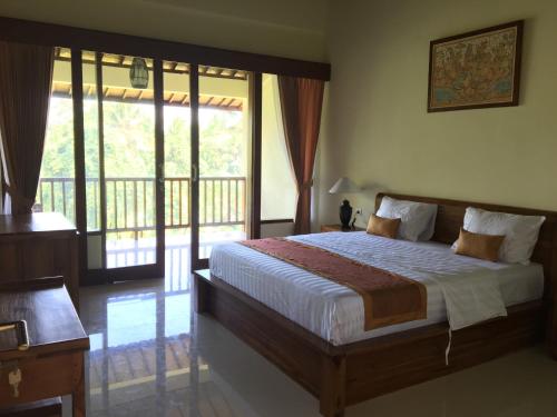 a bedroom with a large bed and a balcony at Raka Rai Bungalows in Ubud