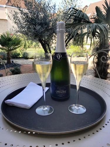 une bouteille de vin et deux verres sur une table dans l'établissement Demeure Saint Martin, à Vertus