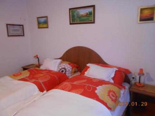 a bedroom with two beds with red and white sheets at Marika Vendégház in Mátraderecske