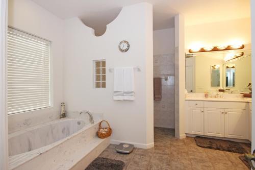 ein weißes Badezimmer mit einer Badewanne, einem Waschbecken und einem Spiegel in der Unterkunft Mangrove Bay SW Cape - waterfront private home locally owned & managed, fair & honest pricing in Cape Coral