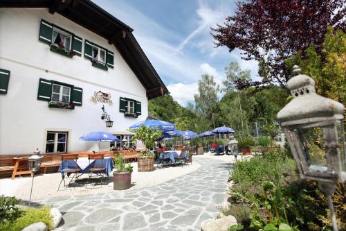 a building with a courtyard with tables and blue umbrellas at Landgasthof & Restaurant Batzenhäusl in Sankt Gilgen